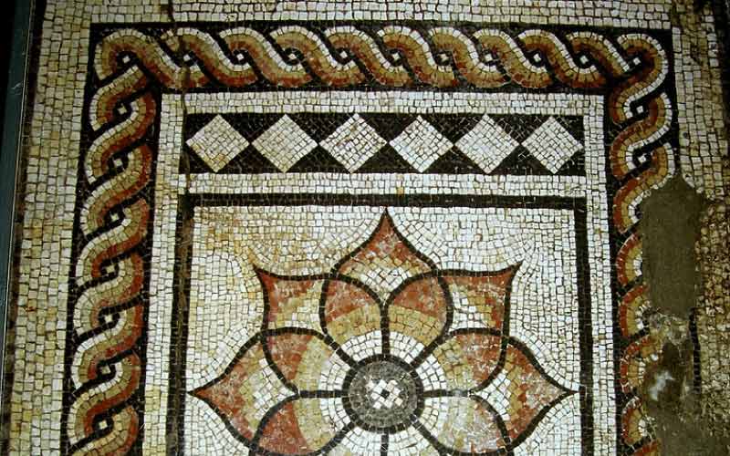 Roman mosaic floor at Canterbury Roman Museum showcasing intricate ancient designs.